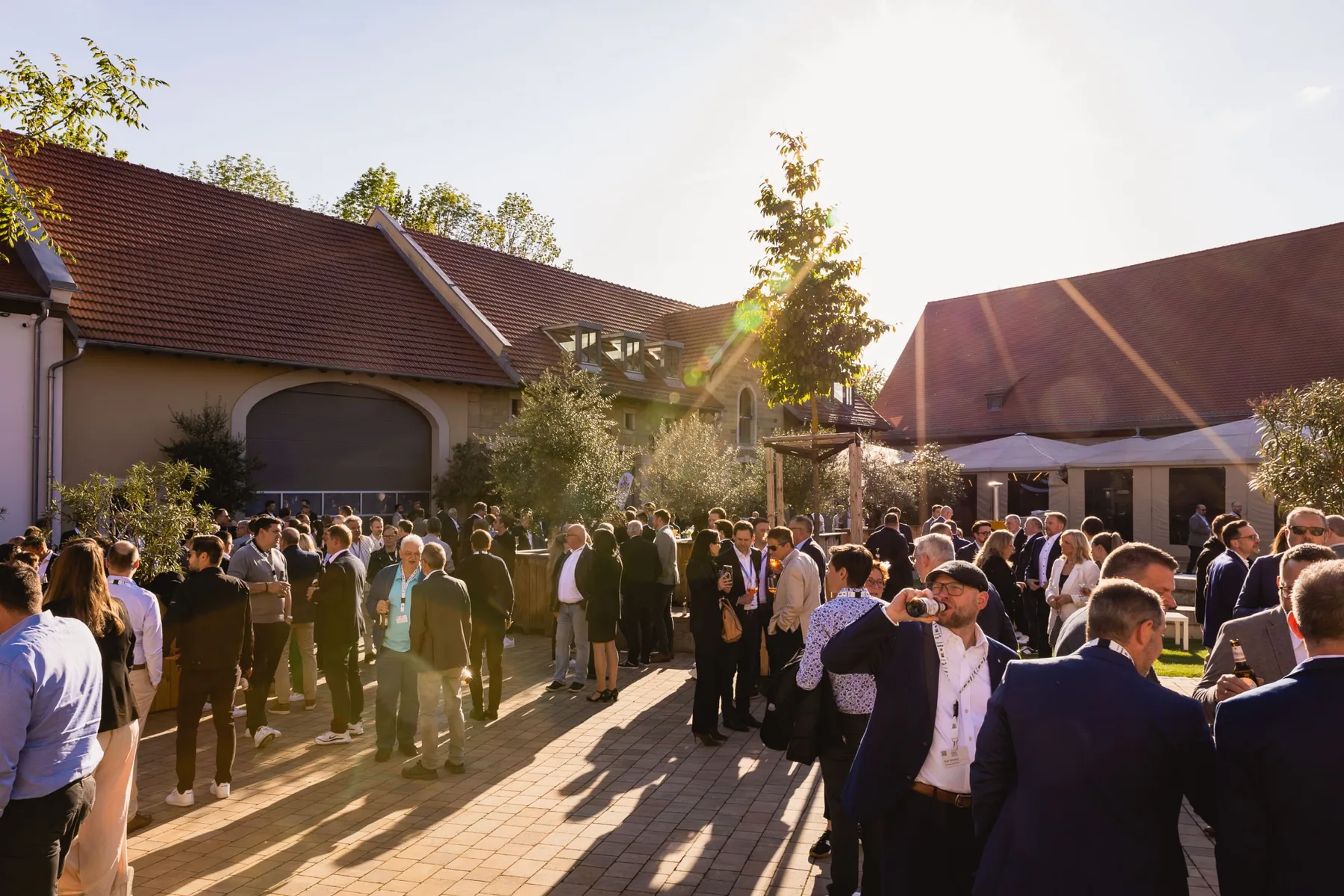 Zahlreiche Gäste bei einem Business-Networking-Event im sonnigen Innenhof von Gut Wöllried