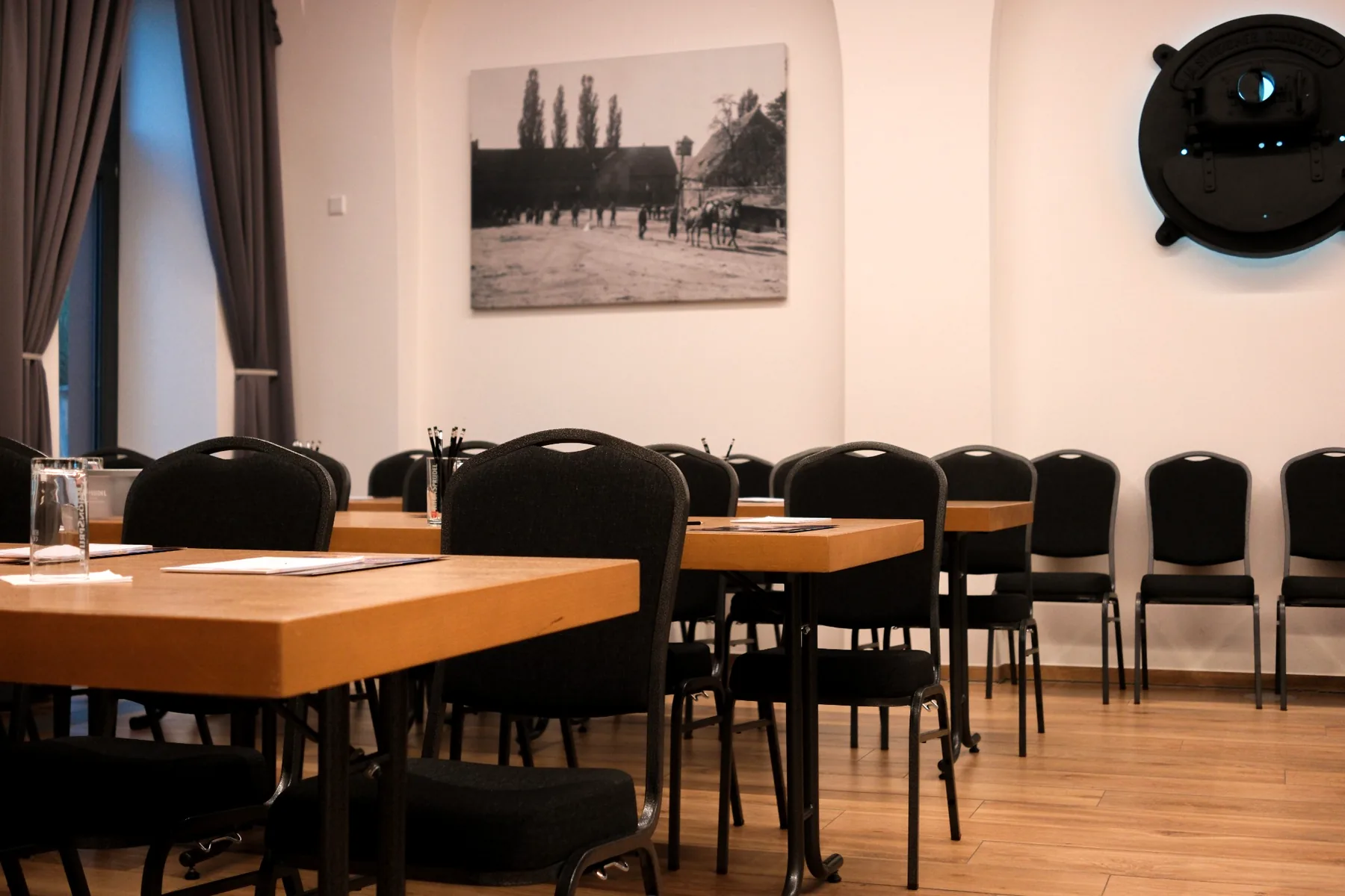 Seminarraum der Brennerei auf Gut Wöllried mit Konferenztischen, schwarzer Bestuhlung und historischen Fotografien