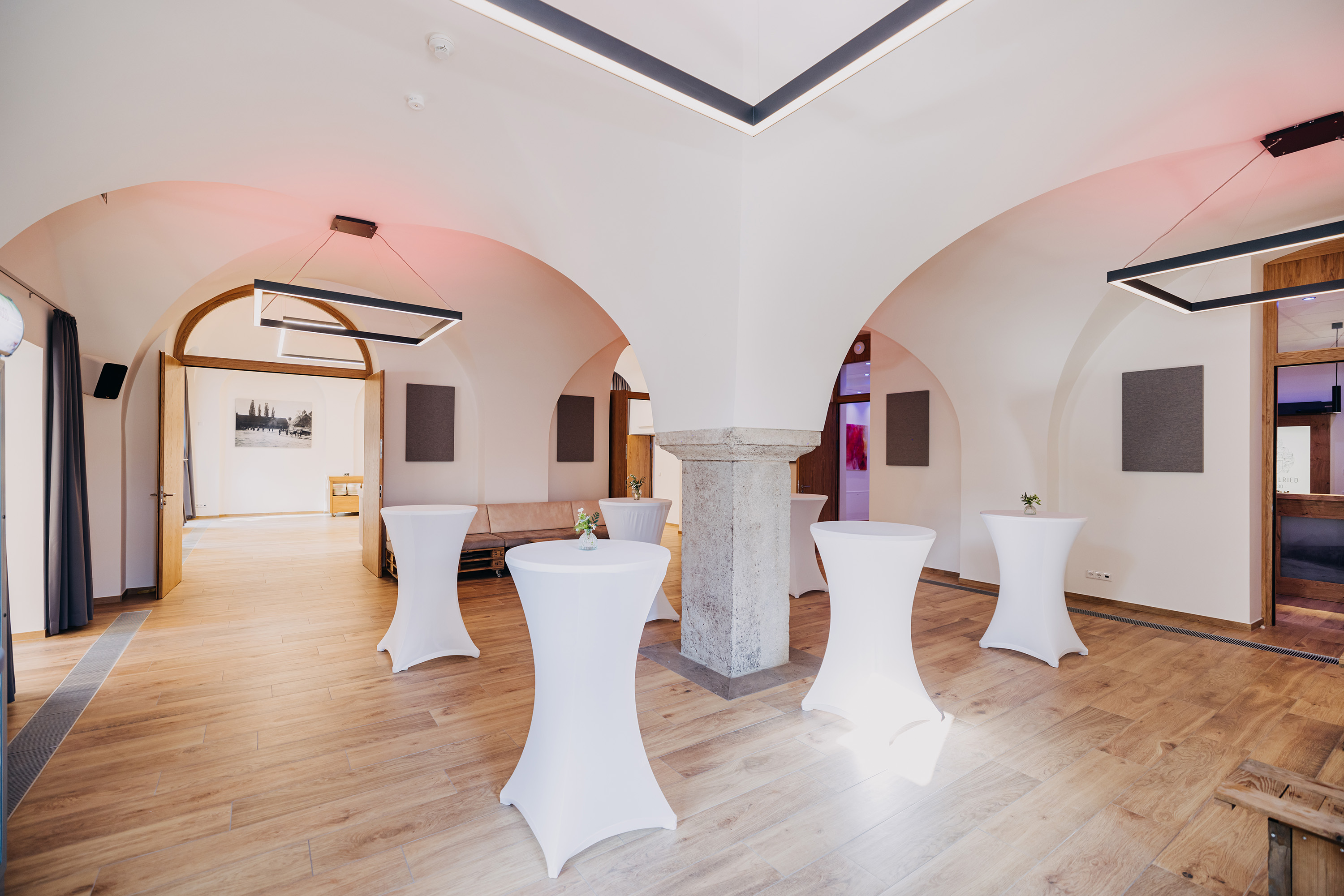 Heller Tagungsraum im Loft der Brennerei auf Gut Wöllried mit grünen Sofas, Konferenztisch und historischem Dachgebälk